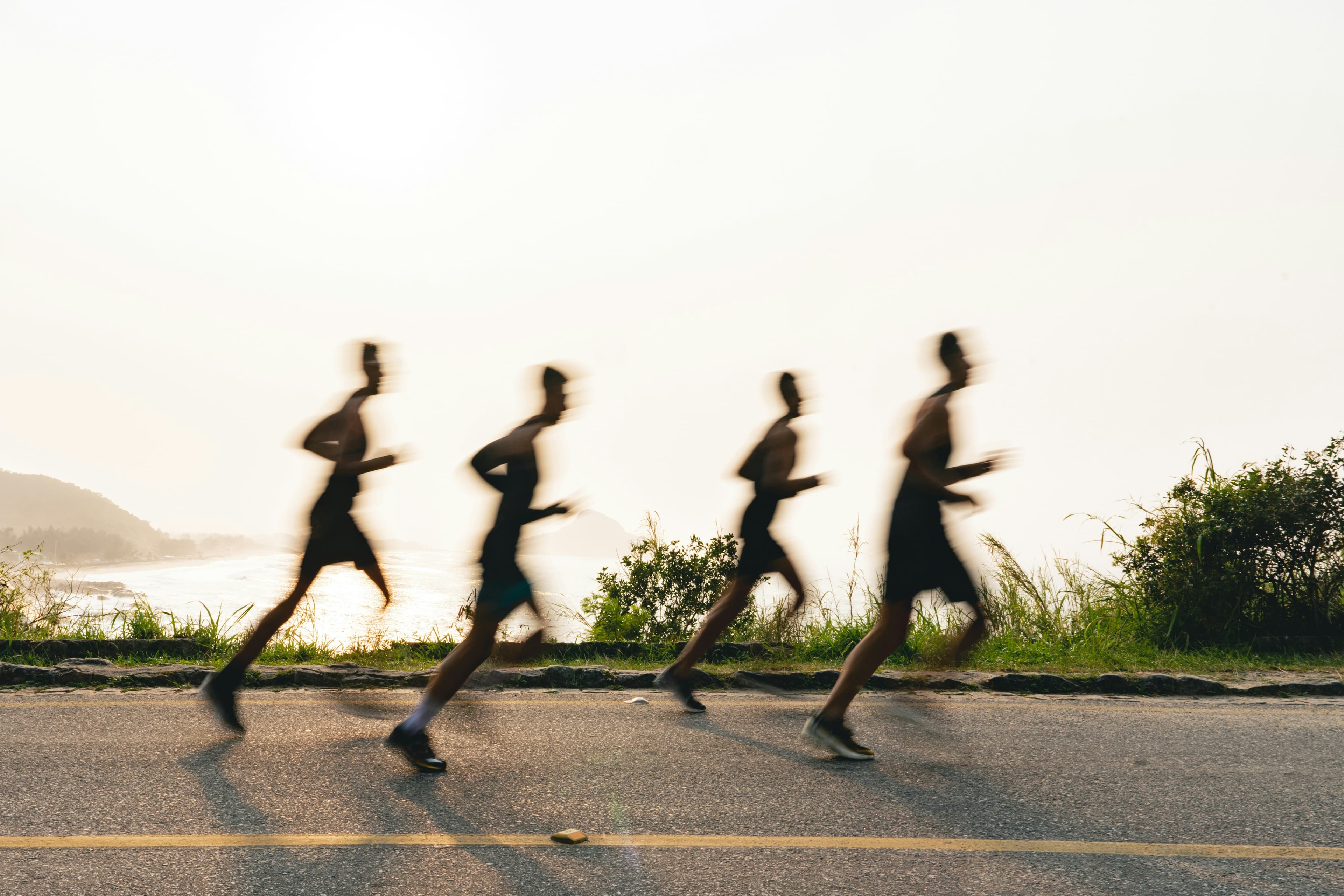Runners on a coastal road at golden hour